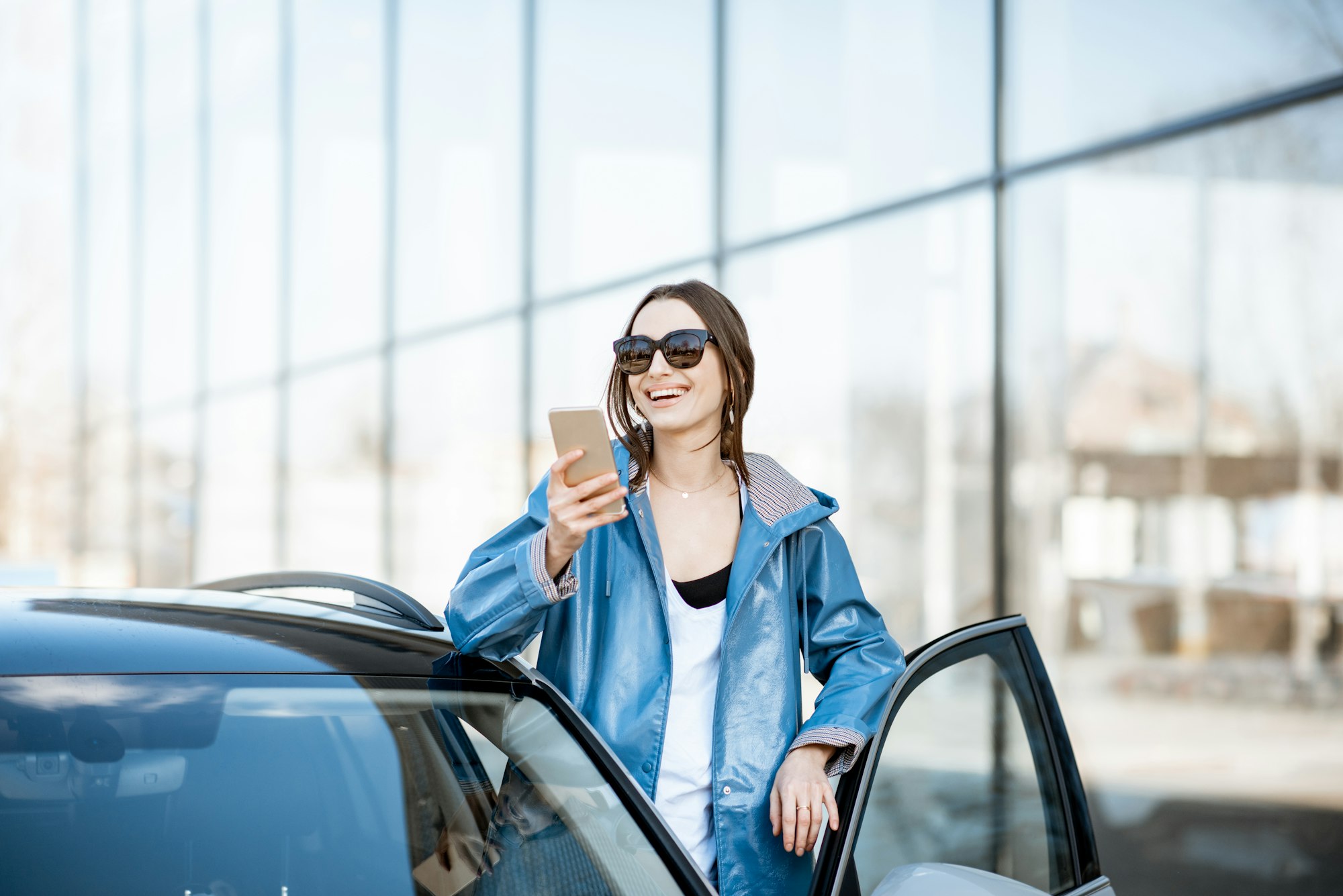 Woman with smart phone near the car outdoors